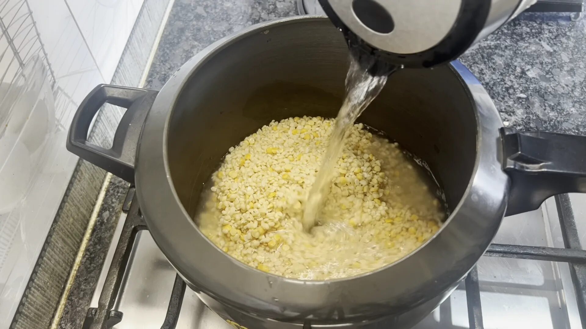 Adding water to the dal in the pressure cooker